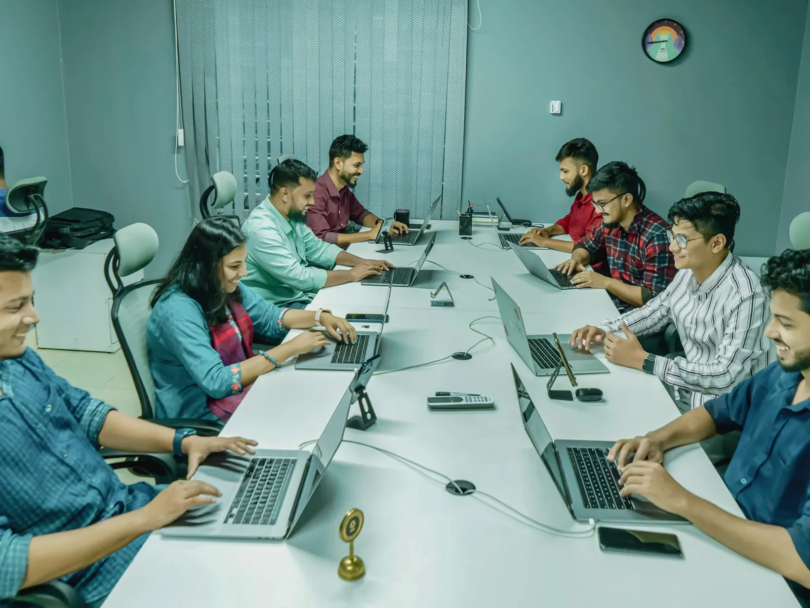 Team working on laptops along a long shared table