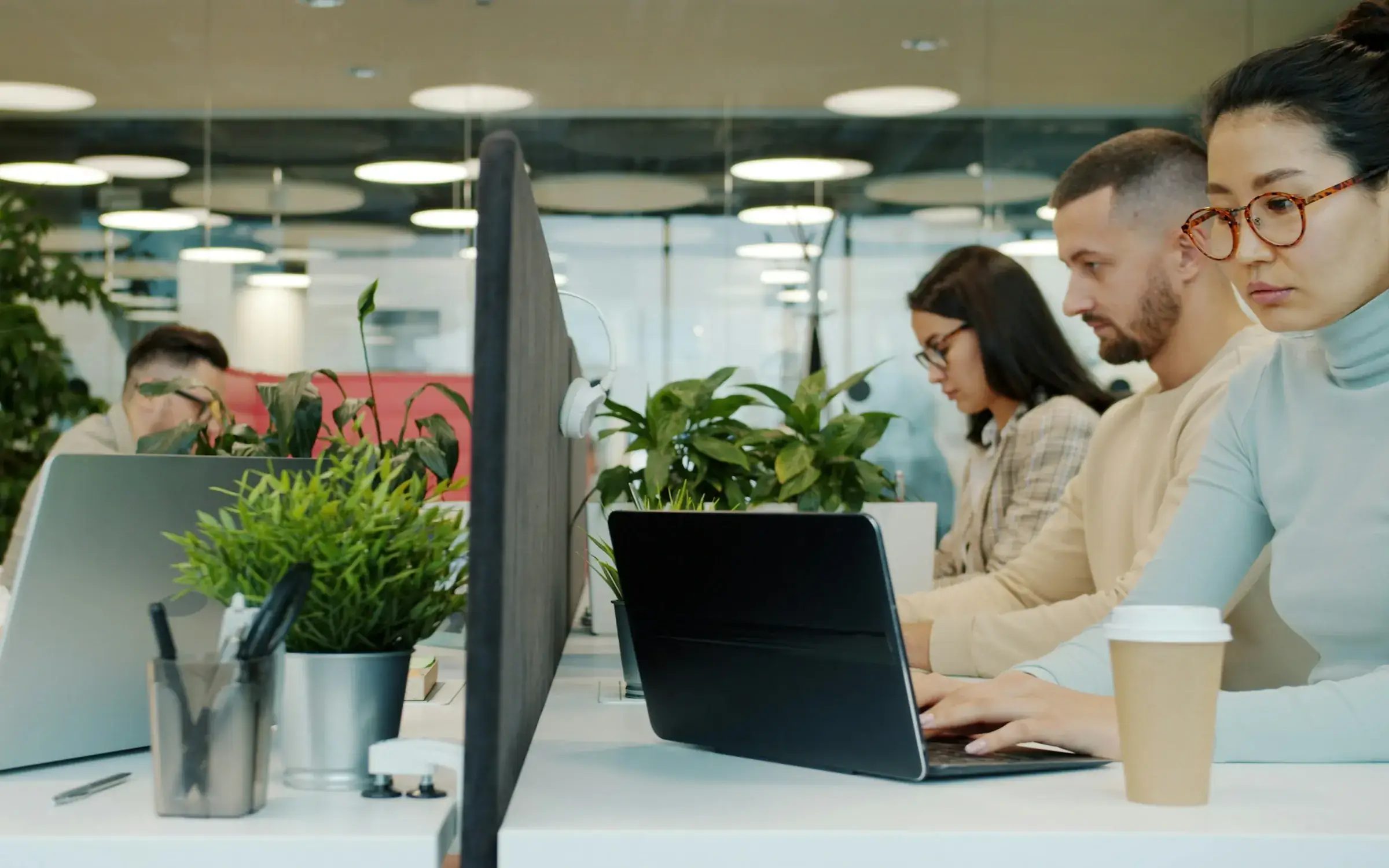 Engineers and analysts working side by side at laptops in a bright open-plan office