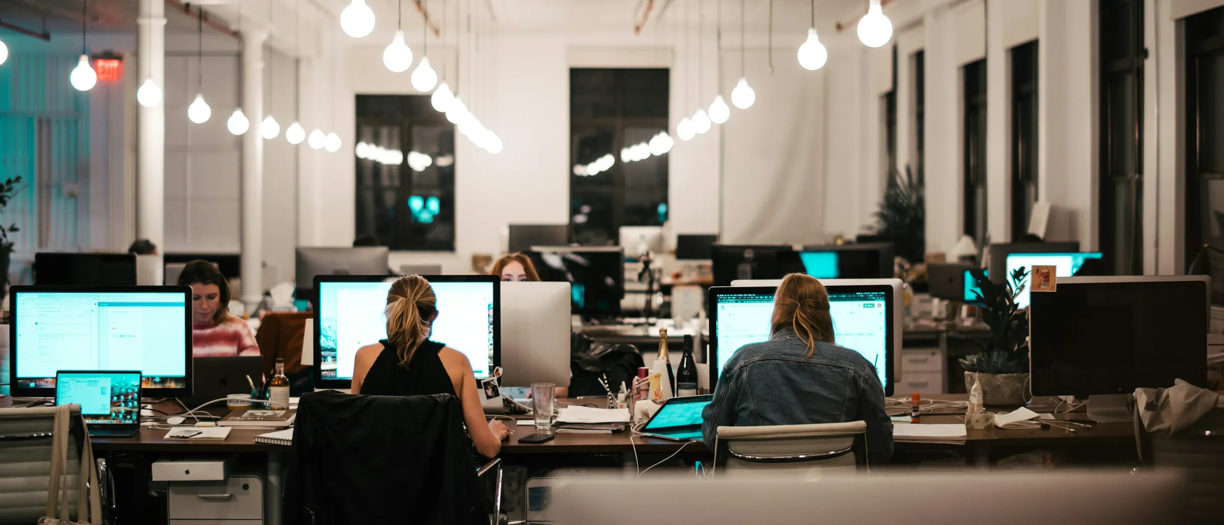 Team members working at rows of desktop screens in a busy open office